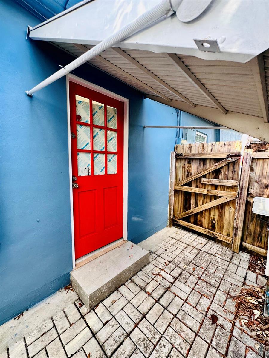 A red door with glass panes sits on a patio next to a wooden fence — 1118 N E Street, FL 33460, FL