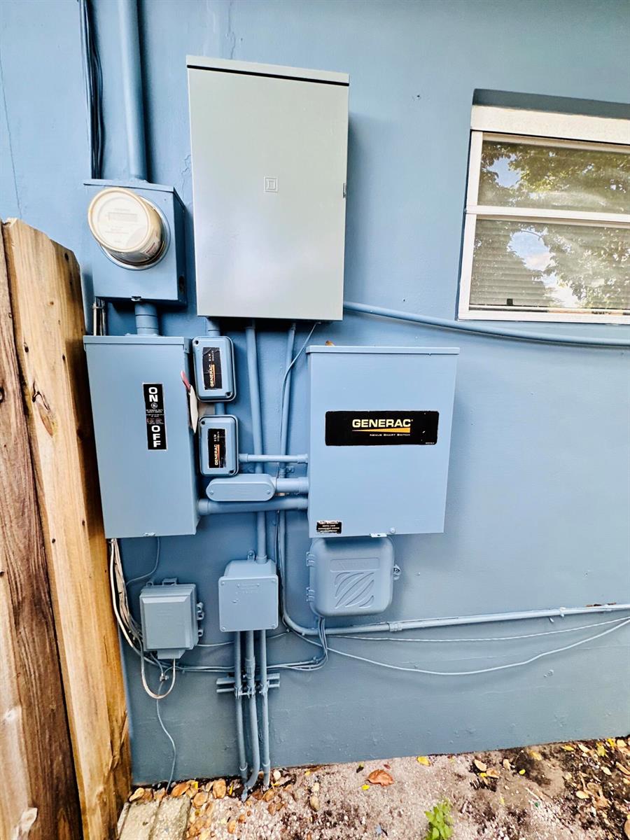 An exterior wall features a utility meter, a Generac transfer switch, and electrical conduit boxes — 1118 N E Street, FL 33460, FL