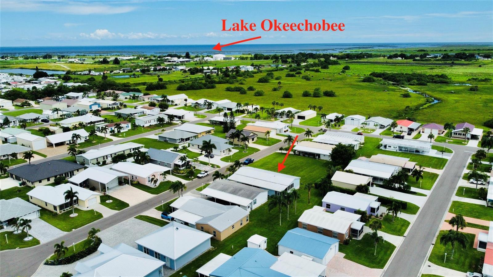 An aerial view shows a residential neighborhood with a large lake in the background — 4331 SW 10th Way, Okeechobee FL 34974, OKEECHOBEE, FL