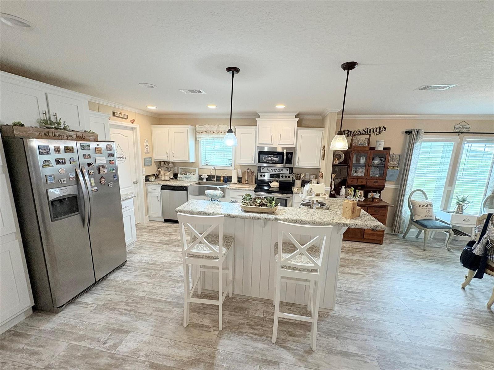 A kitchen features white cabinetry, granite countertops, stainless steel appliances, and a central island — 4331 SW 10th Way, Okeechobee FL 34974, OKEECHOBEE, FL