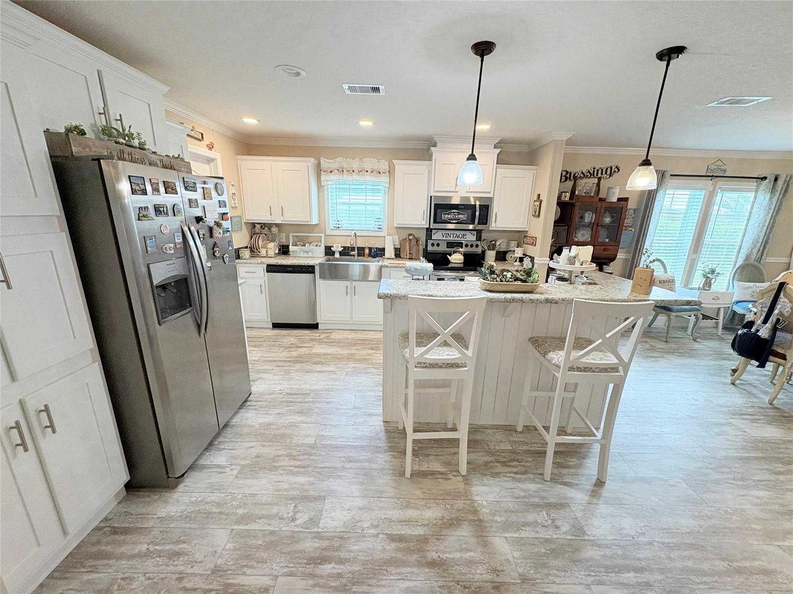 A kitchen features white cabinets, stainless steel appliances, a center island, and wood-look tile flooring — 4331 SW 10th Way, Okeechobee FL 34974, OKEECHOBEE, FL