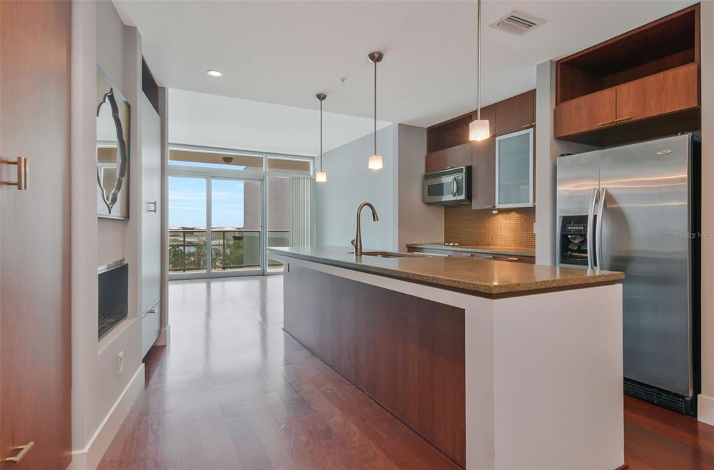 A modern kitchen features a large island, stainless steel appliances, and wood cabinetry — 111 N 12TH STREET UNIT 1608, TAMPA, FL