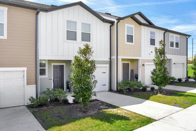 A row of modern townhouses features white vertical siding, tan horizontal siding, and attached garages — 125 MANDOVI STREET, DAVENPORT, FL