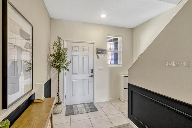 An entryway features a white door, a potted plant, a wooden console table, and wainscoting — 125 MANDOVI STREET, DAVENPORT, FL