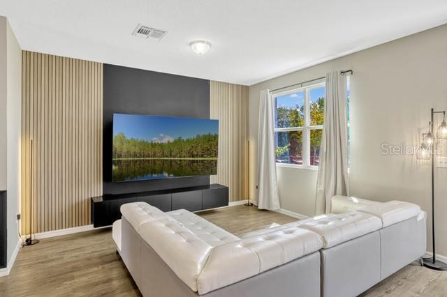 A living room features a large television mounted on a black and wood-slatted accent wall — 125 MANDOVI STREET, DAVENPORT, FL