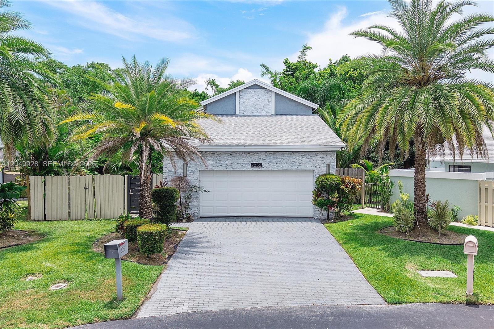 A single-story house with a white stone facade, a two-car garage, and palm trees — 2055 NW 9th St, Delray Beach FL 33445, DELRAY BEACH, FL