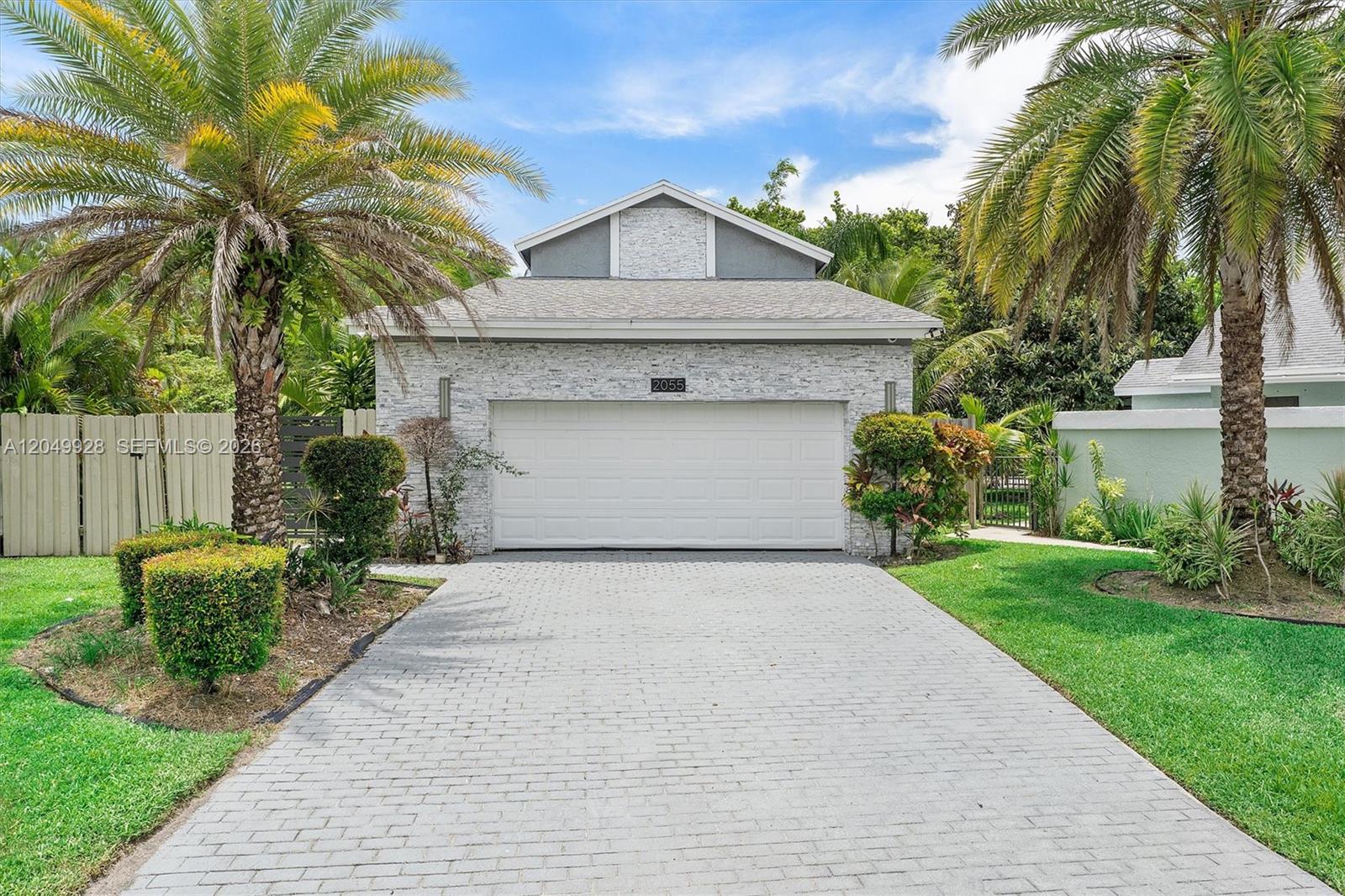 A single-story house features a stone facade, a two-car garage, and two large palm trees — 2055 NW 9th St, Delray Beach FL 33445, DELRAY BEACH, FL