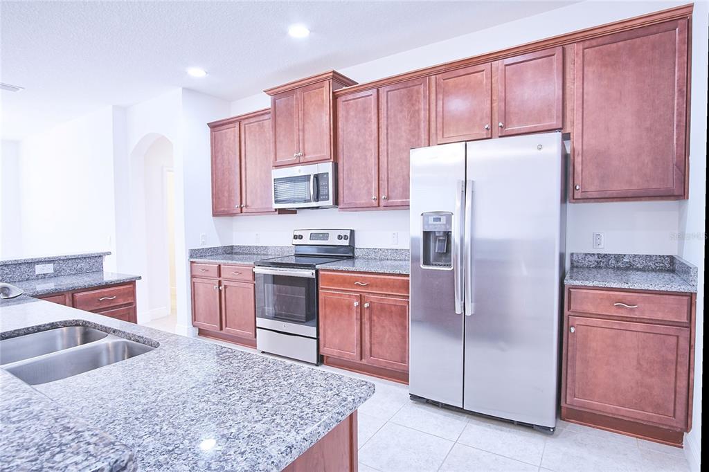 A kitchen featuring wood cabinets, granite countertops, and stainless steel appliances — 11619 IRIS SPRING COURT, RIVERVIEW, FL
