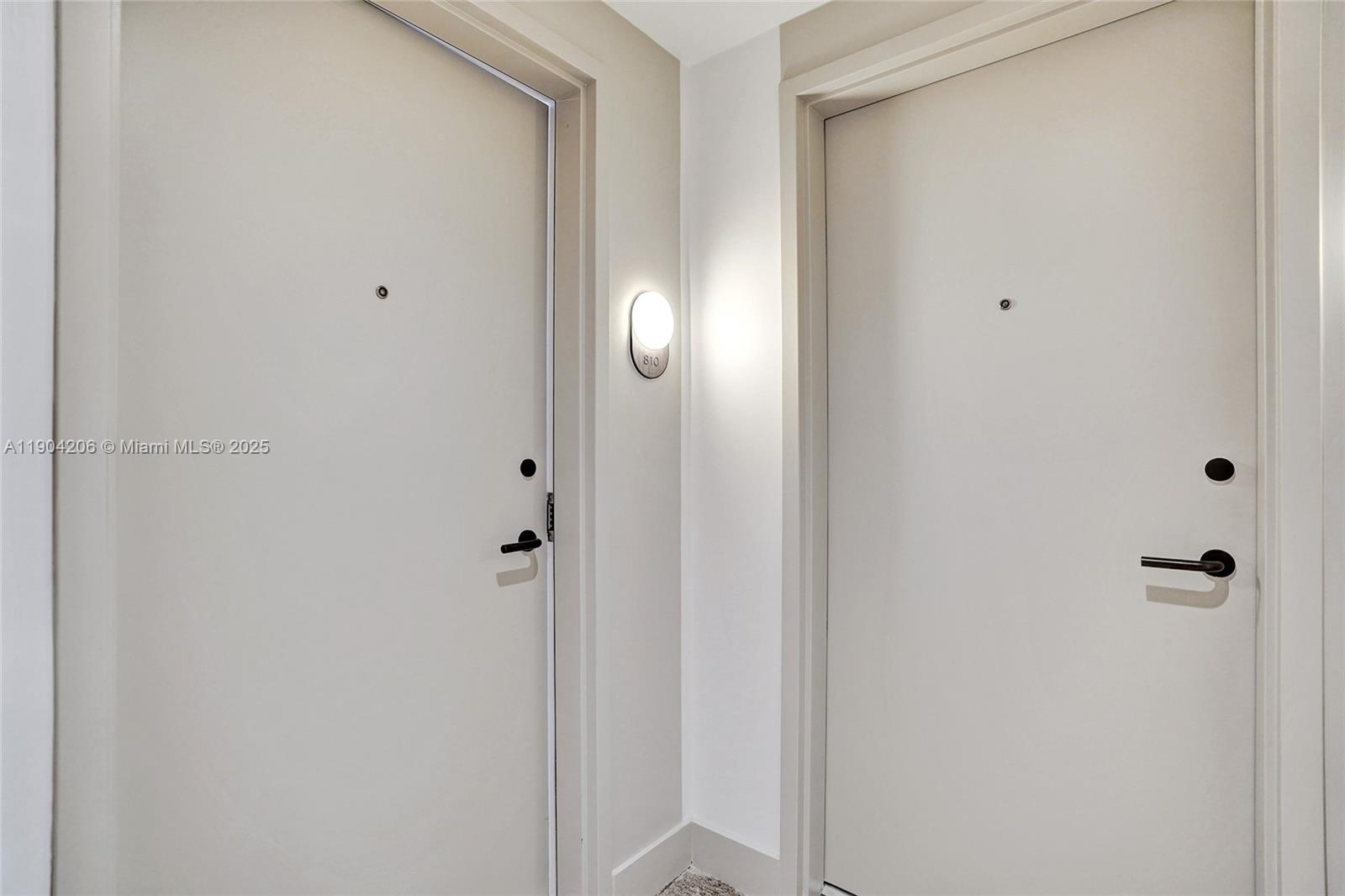 Two plain white apartment doors are positioned next to each other in a hallway — 580 72nd St # 810, Miami Beach FL 33141, MIAMI BEACH, FL