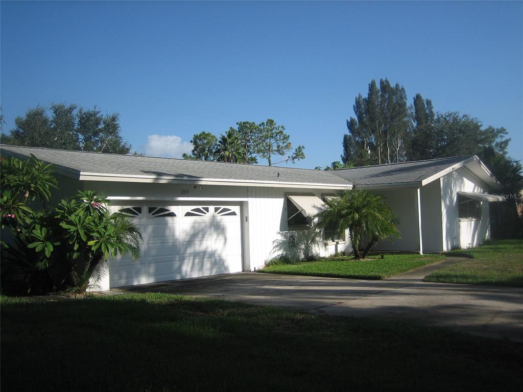 A single-story white house with a two-car garage and a concrete driveway — 2245 CEDAR DRIVE, DUNEDIN, FL