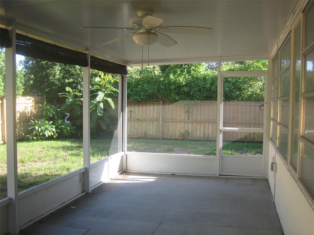 A screened-in porch with a ceiling fan, concrete floor, and a view of the backyard — 2245 CEDAR DRIVE, DUNEDIN, FL