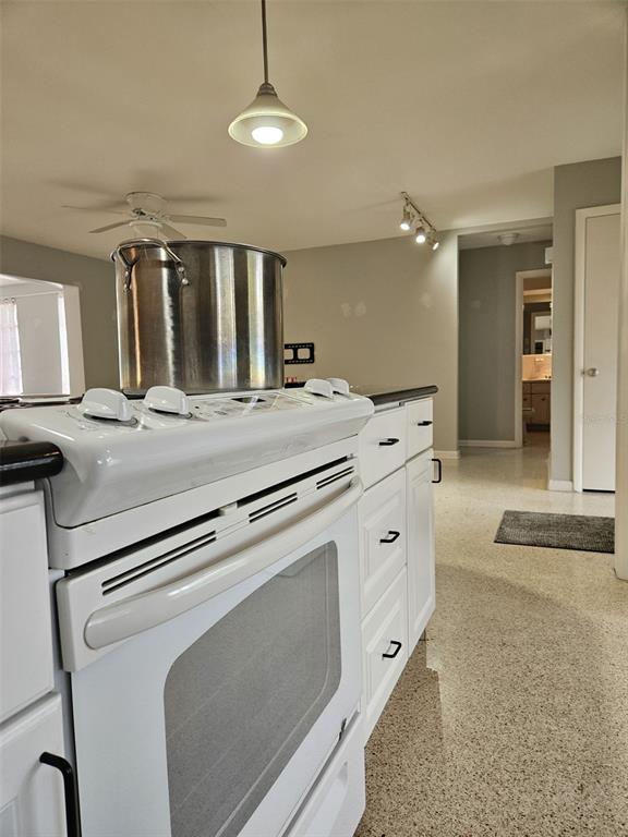 A kitchen features a white stove with a large metal pot and terrazzo flooring — 2245 CEDAR DRIVE, DUNEDIN, FL