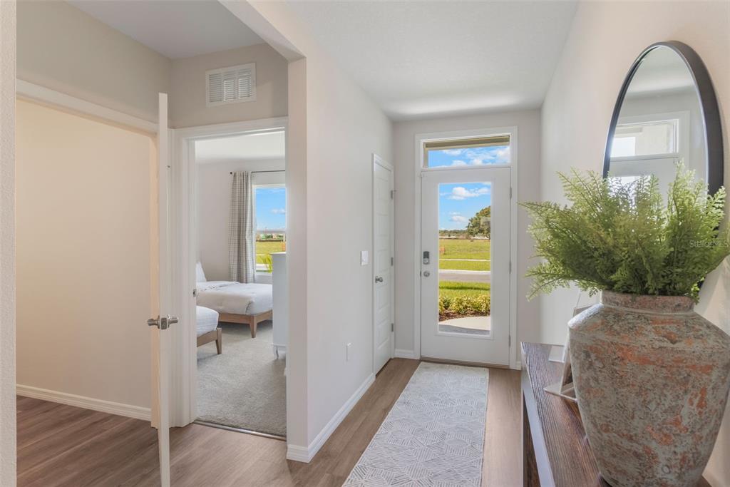 An entryway with wood-look flooring, a glass-paneled front door, and a view into a bedroom — 1779 GRANDIOSE DRIVE, HAINES CITY, FL