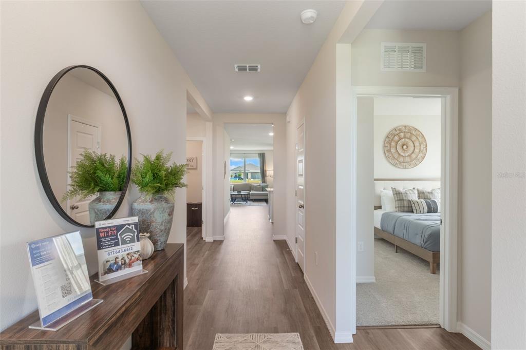A hallway with wood-look flooring leads to a living area, with a bedroom visible on the right — 1779 GRANDIOSE DRIVE, HAINES CITY, FL
