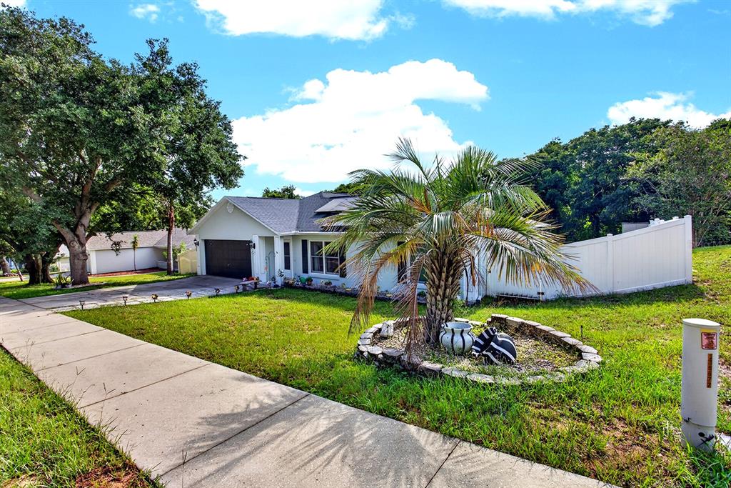 A single-story house with a dark garage door, solar panels, and a concrete paver walkway — 919 ARBOR HILL CIR, MINNEOLA, FL