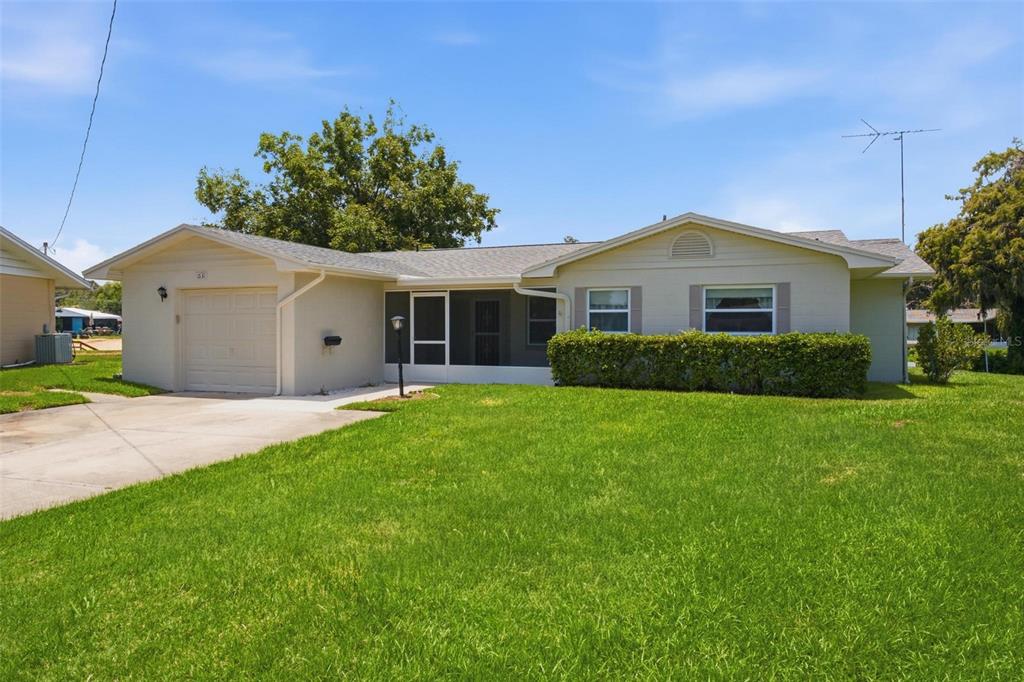 A single-story house with a beige exterior, a one-car garage, and a screened front porch — 1631 CANAL COURT, TAVARES, FL
