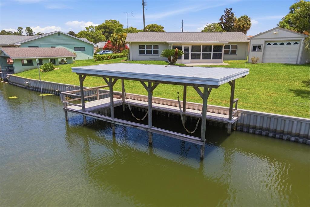 An aerial view of a boat lift and dock extending into a canal behind a house — 1631 CANAL COURT, TAVARES, FL