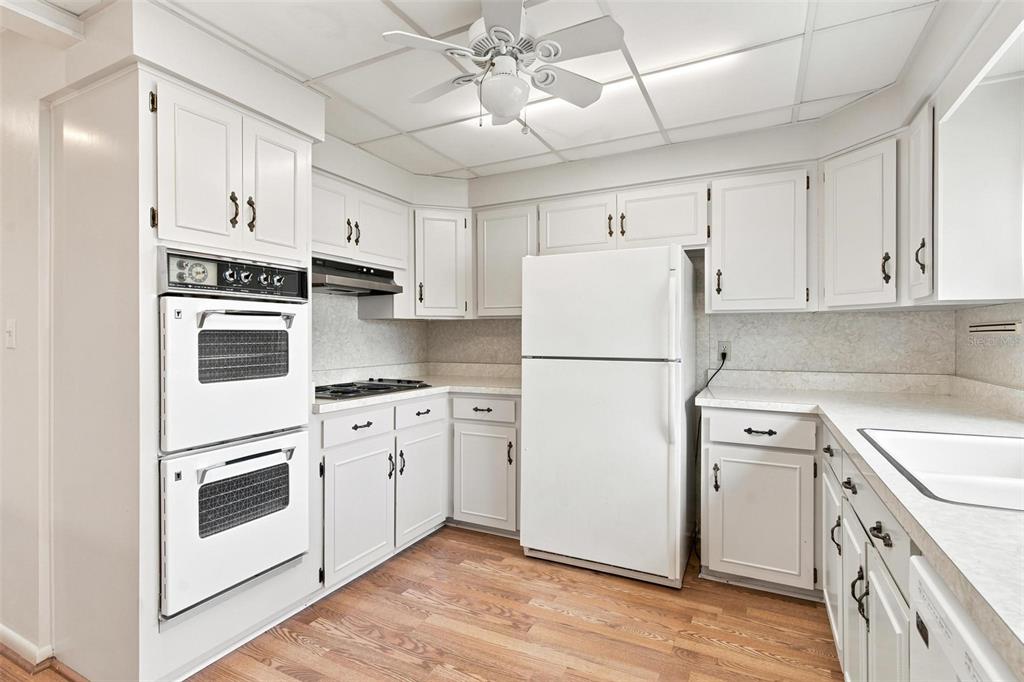 A kitchen with white cabinets, a double wall oven, a gas cooktop, and wood flooring — 1631 CANAL COURT, TAVARES, FL