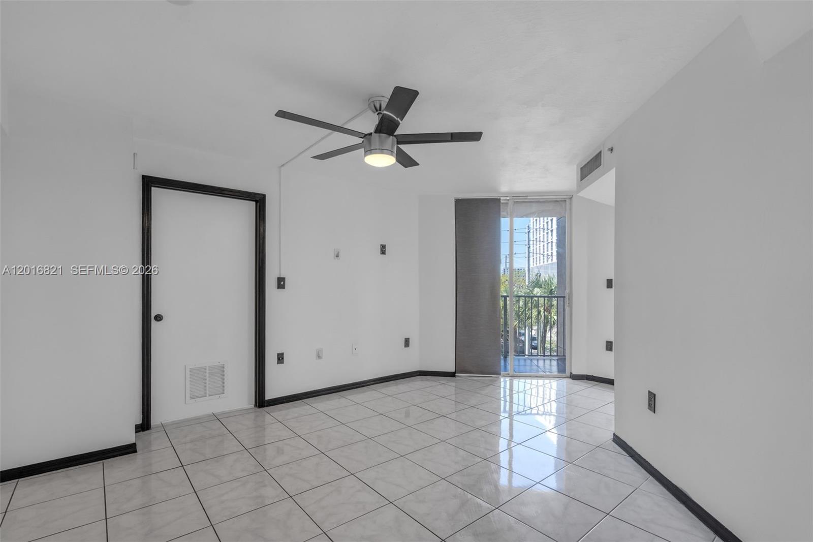 An empty room features white walls, black trim, tile flooring, a ceiling fan, and a balcony — 102 SW 6th Ave # 201, Miami FL 33130, MIAMI, FL