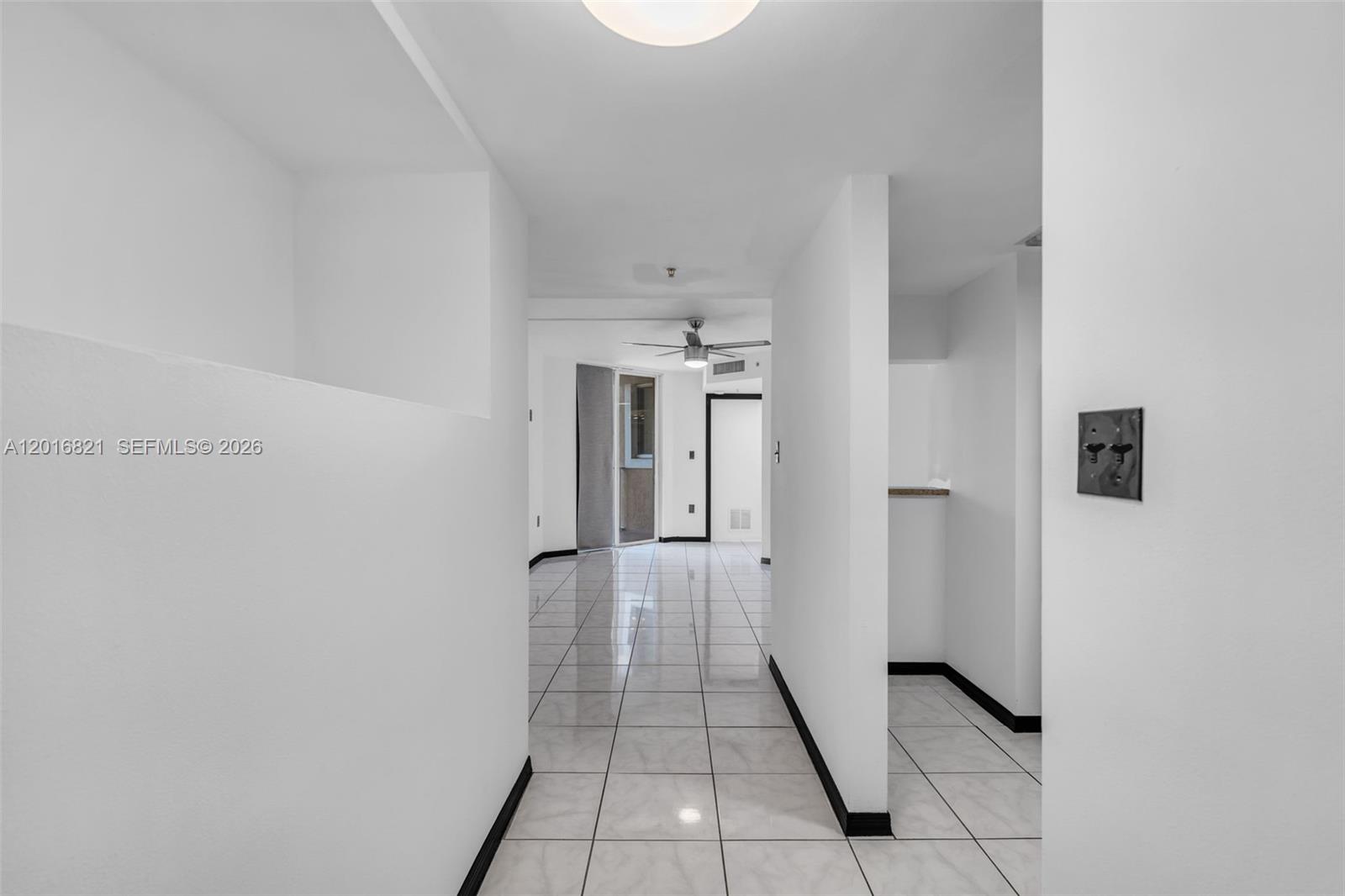A bright hallway with white walls and light-colored tile flooring leads toward a living area — 102 SW 6th Ave # 201, Miami FL 33130, MIAMI, FL