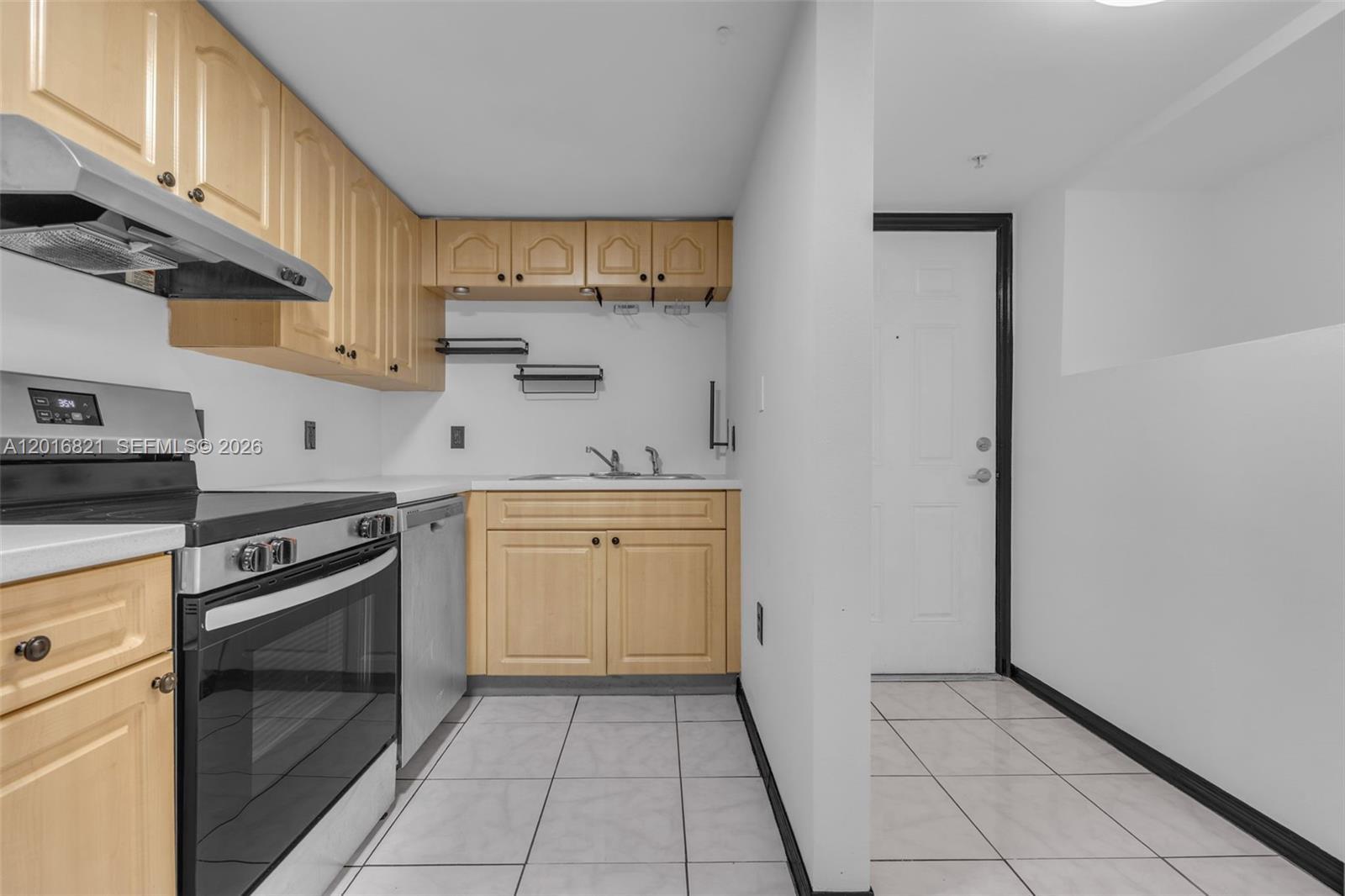 A small kitchen features light wood cabinets, stainless steel appliances, and white tile flooring — 102 SW 6th Ave # 201, Miami FL 33130, MIAMI, FL