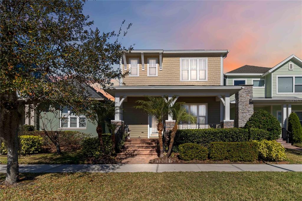 A two-story house with a front porch, tan siding, and a stone-accented pillar — 8905 LAUREATE BOULEVARD, ORLANDO, FL