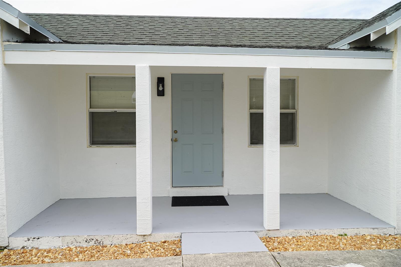 A front porch with a light blue door, two windows, and white support columns — 908 W 5th Street, Riviera Beach FL 33404, RIVIERA BEACH, FL