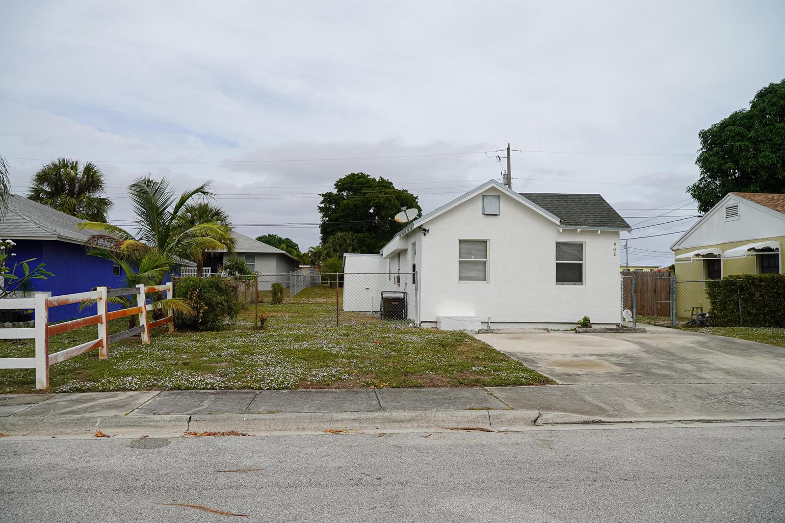 A white, single-story house with a concrete driveway and a fenced front yard — 908 W 5th Street, Riviera Beach FL 33404, RIVIERA BEACH, FL