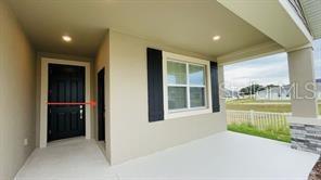 A covered porch features a dark front door, a window with shutters, and a concrete floor — 905 CITRUS RESERVE BOULEVARD UNIT B, DAVENPORT, FL