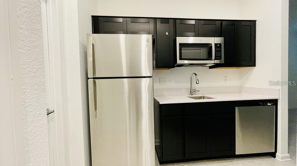 A kitchen features dark cabinets, stainless steel appliances, and white countertops — 905 CITRUS RESERVE BOULEVARD UNIT B, DAVENPORT, FL
