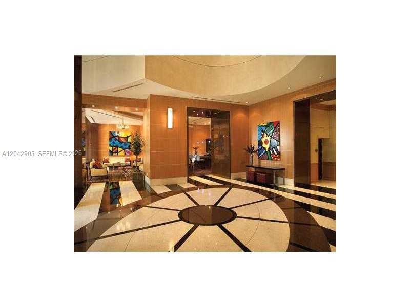 A modern lobby features a circular patterned floor, wood-paneled walls, and colorful abstract artwork — 244 Biscayne Blvd # 240, Miami FL 33132, MIAMI, FL