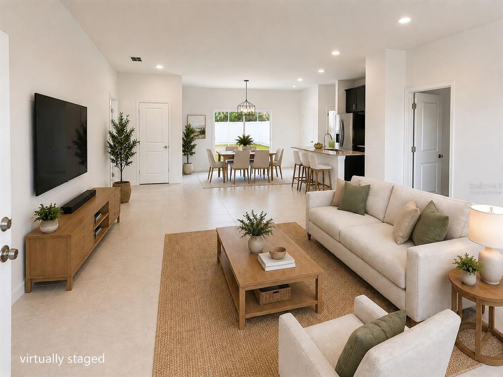 A virtually staged open-concept living and dining area with light tile flooring and white walls — 2701 W TRACY COURT, DUNNELLON, FL