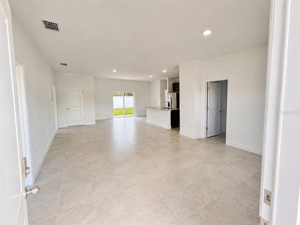 An open-concept living area with light tile flooring, a kitchen island, and sliding glass doors — 2701 W TRACY COURT, DUNNELLON, FL