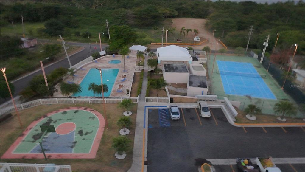 An aerial view shows a community recreation area with a swimming pool, tennis court, and basketball court — Cond. VILLAS DEL FARO UNIT 3-301, MAUNABO, PR