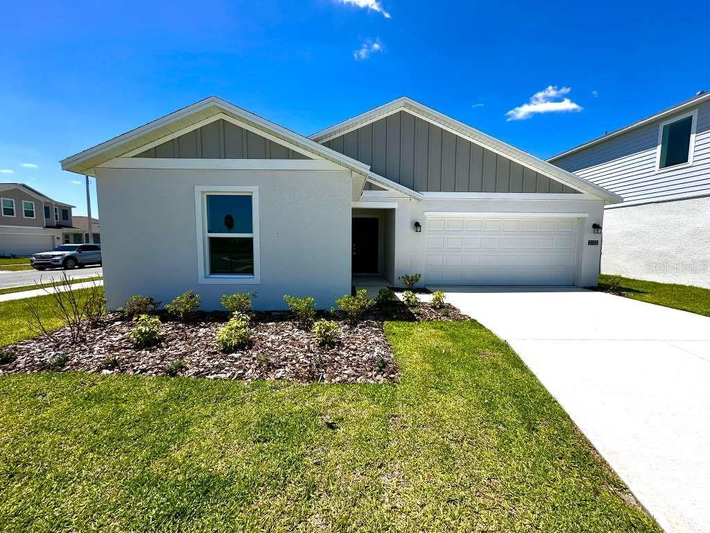 A single-story house with a white garage, gray siding, and a landscaped front yard — 2102 CHRIS DRIVE, WINTER HAVEN, FL