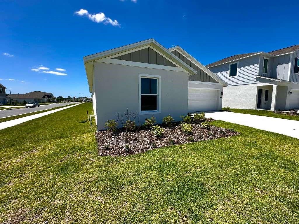 A single-story house with a light-colored stucco exterior, a garage, and a landscaped front yard — 2102 CHRIS DRIVE, WINTER HAVEN, FL