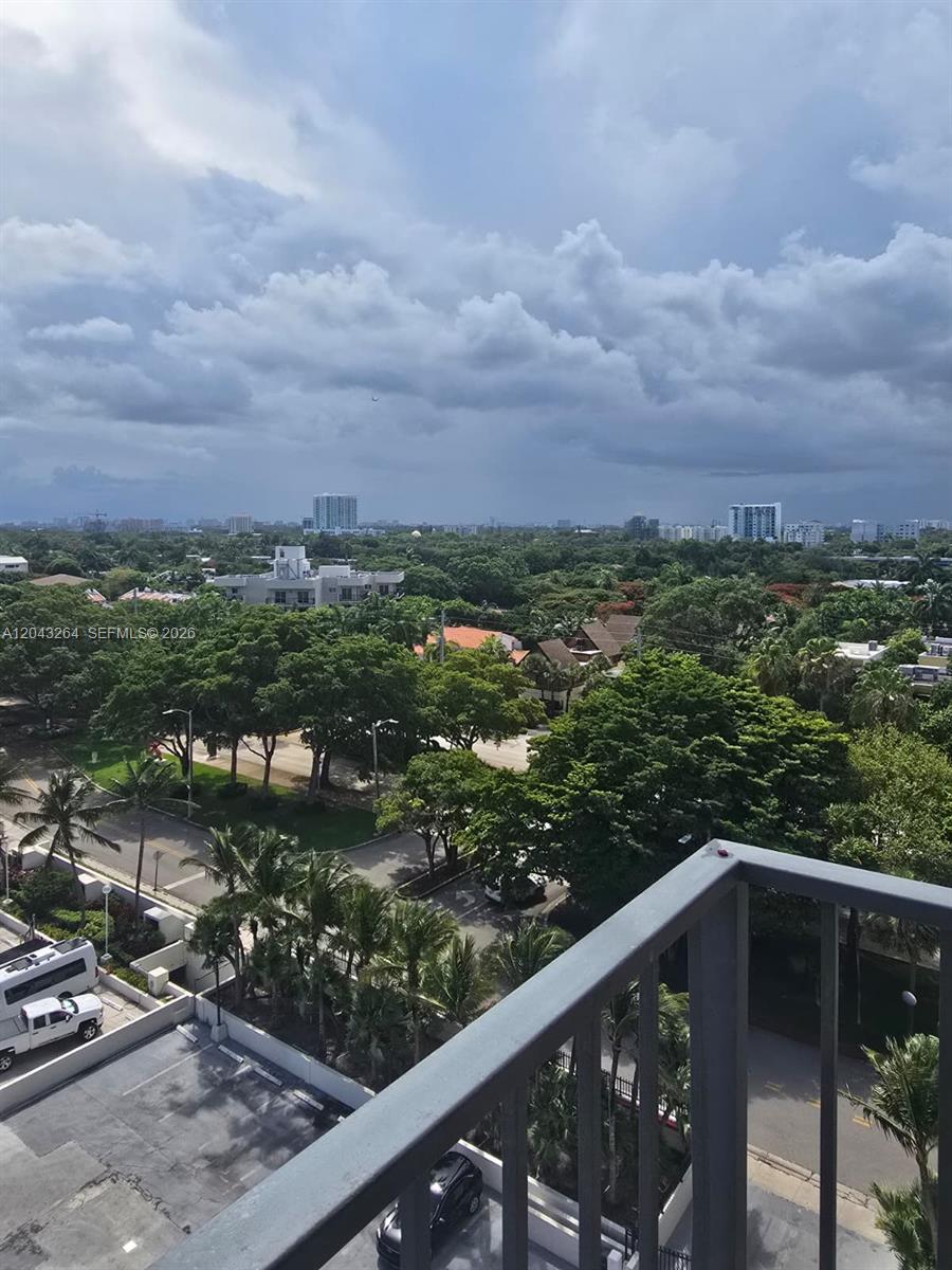 A view from a balcony overlooking a parking lot, lush trees, and distant city buildings — 1901 Brickell Ave # B1007, Miami FL 33129, MIAMI, FL