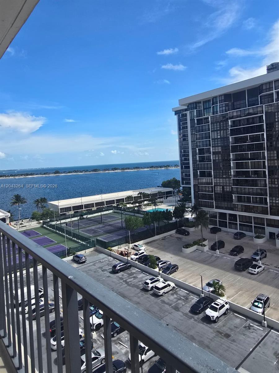 A high-angle view shows a parking lot, tennis courts, and a bay with a distant shoreline — 1901 Brickell Ave # B1007, Miami FL 33129, MIAMI, FL