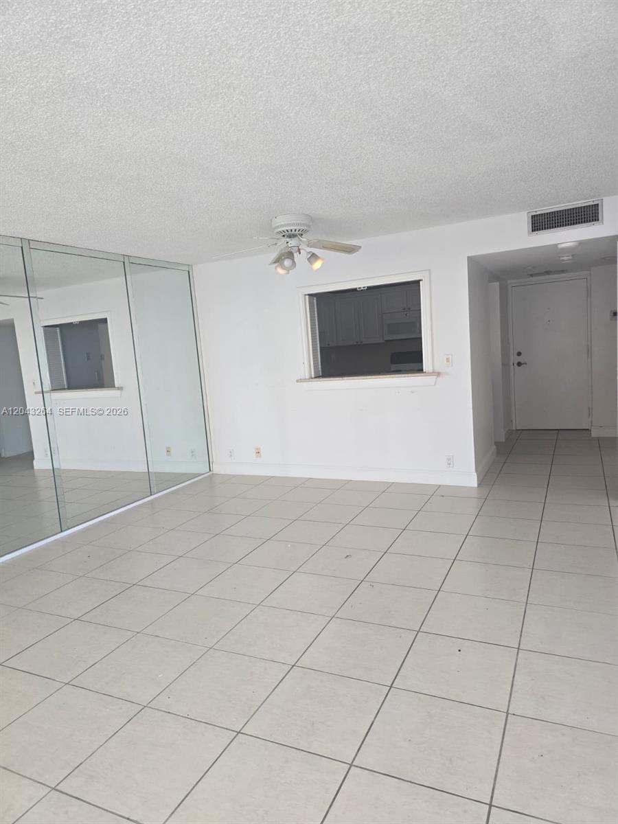 This room features white tile flooring, a mirrored wall, and a kitchen pass-through window — 1901 Brickell Ave # B1007, Miami FL 33129, MIAMI, FL