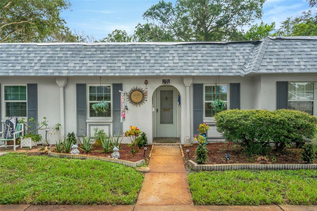 A single-story house with a gray shingled roof, blue shutters, and a central arched entryway — 4252 SHELDON PLACE UNIT 4252, NEW PORT RICHEY, FL
