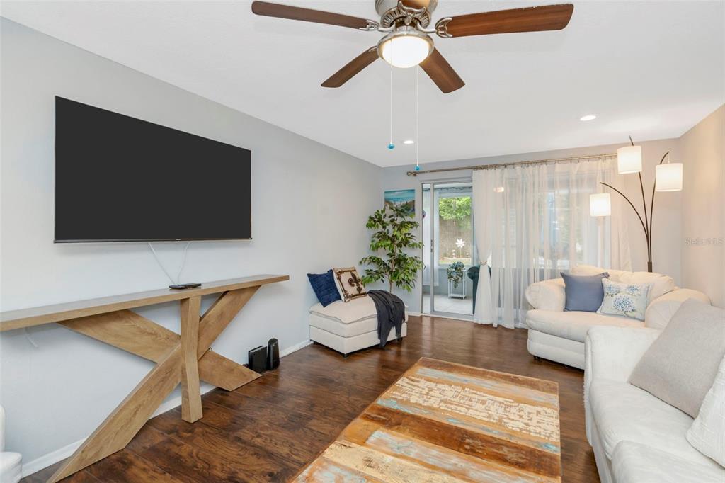 A living room features a wall-mounted television, a wooden console table, and white furniture — 4252 SHELDON PLACE UNIT 4252, NEW PORT RICHEY, FL