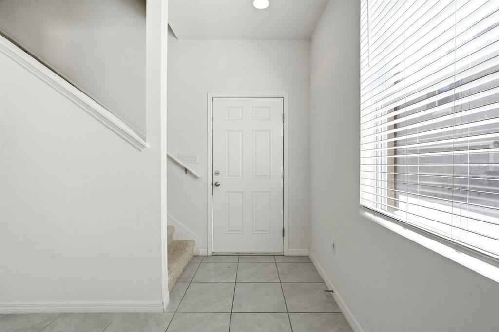 An entryway with light tile flooring, a white front door, and stairs leading upward — 1680 COULTER LANE, PORT ORANGE, FL