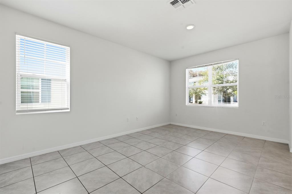 An empty room with light gray tile flooring, white walls, and two windows with blinds — 1680 COULTER LANE, PORT ORANGE, FL