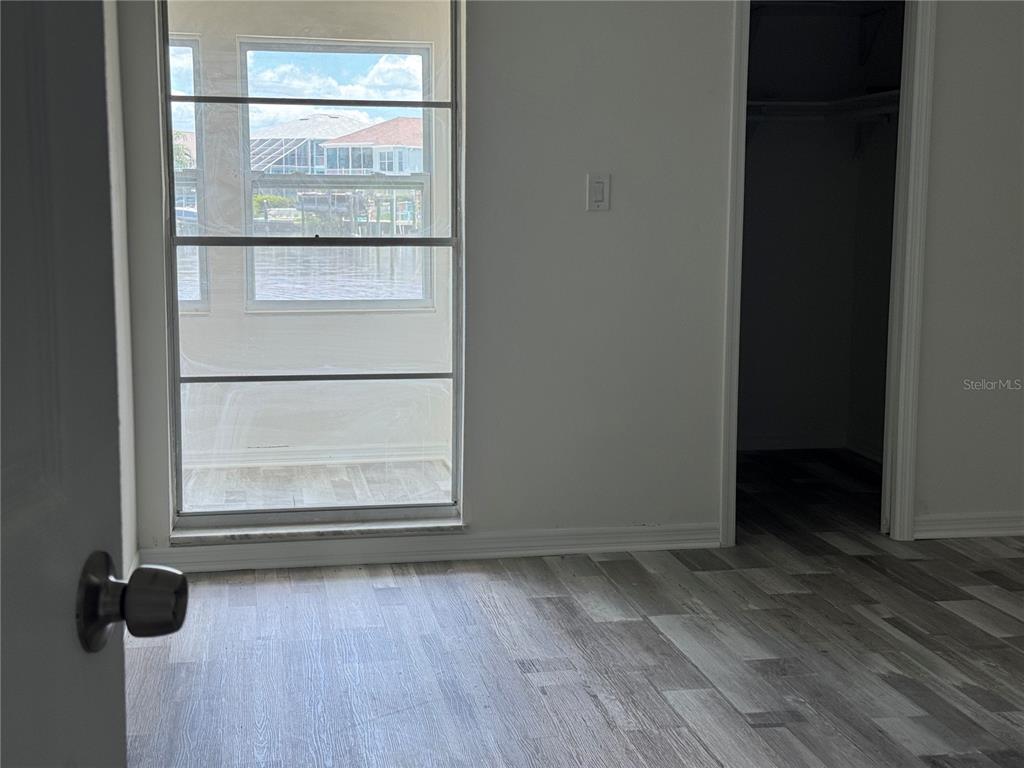 A room with wood-look flooring, a window overlooking a canal, and an open closet — 4609 MARINE PARKWAY UNIT 102, NEW PORT RICHEY, FL