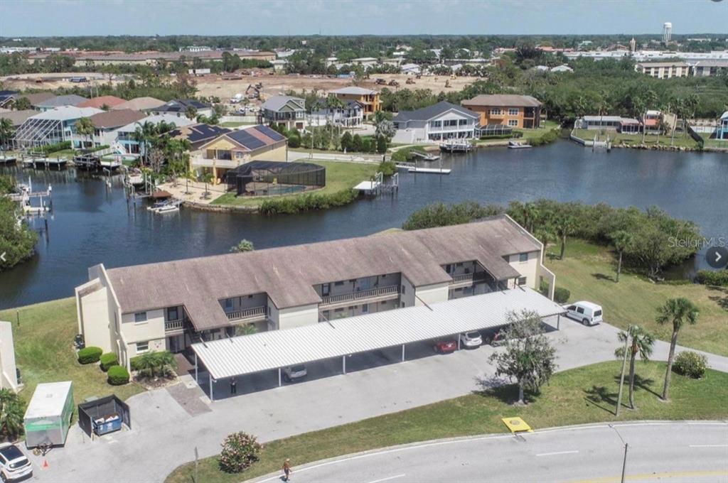 An aerial view shows a multi-story apartment building with a covered parking area near water — 4609 MARINE PARKWAY UNIT 102, NEW PORT RICHEY, FL