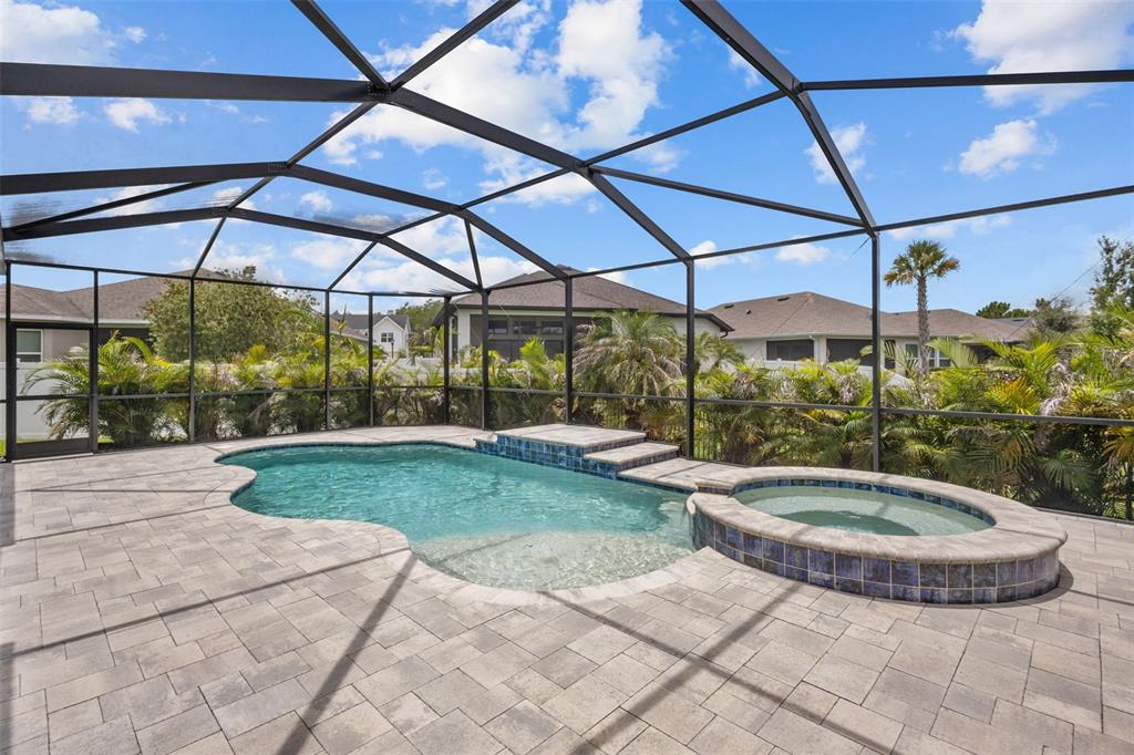 A screened-in patio features a swimming pool with an attached spa and paver decking — 3164 SATILLA LOOP, ODESSA, FL