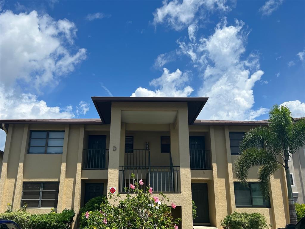 A two-story apartment building exterior features tan stucco walls, dark trim, and a central entryway — 3221 WHITE IBIS COURT UNIT D3, PUNTA GORDA, FL