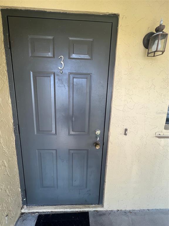 A gray six-panel front door with the number three is set in a stucco wall — 3221 WHITE IBIS COURT UNIT D3, PUNTA GORDA, FL