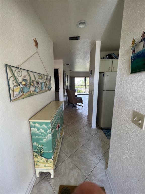 A tiled hallway leads past a painted cabinet toward a living area with a balcony view — 3221 WHITE IBIS COURT UNIT D3, PUNTA GORDA, FL