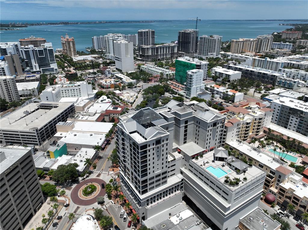 An aerial view shows a high-rise building with a rooftop pool in a coastal city — 50 CENTRAL AVENUE UNIT 970, SARASOTA, FL